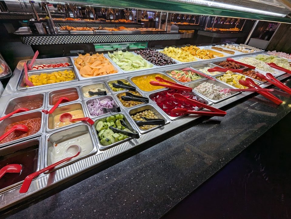 Hibachi grill station beside trays of prepared food.